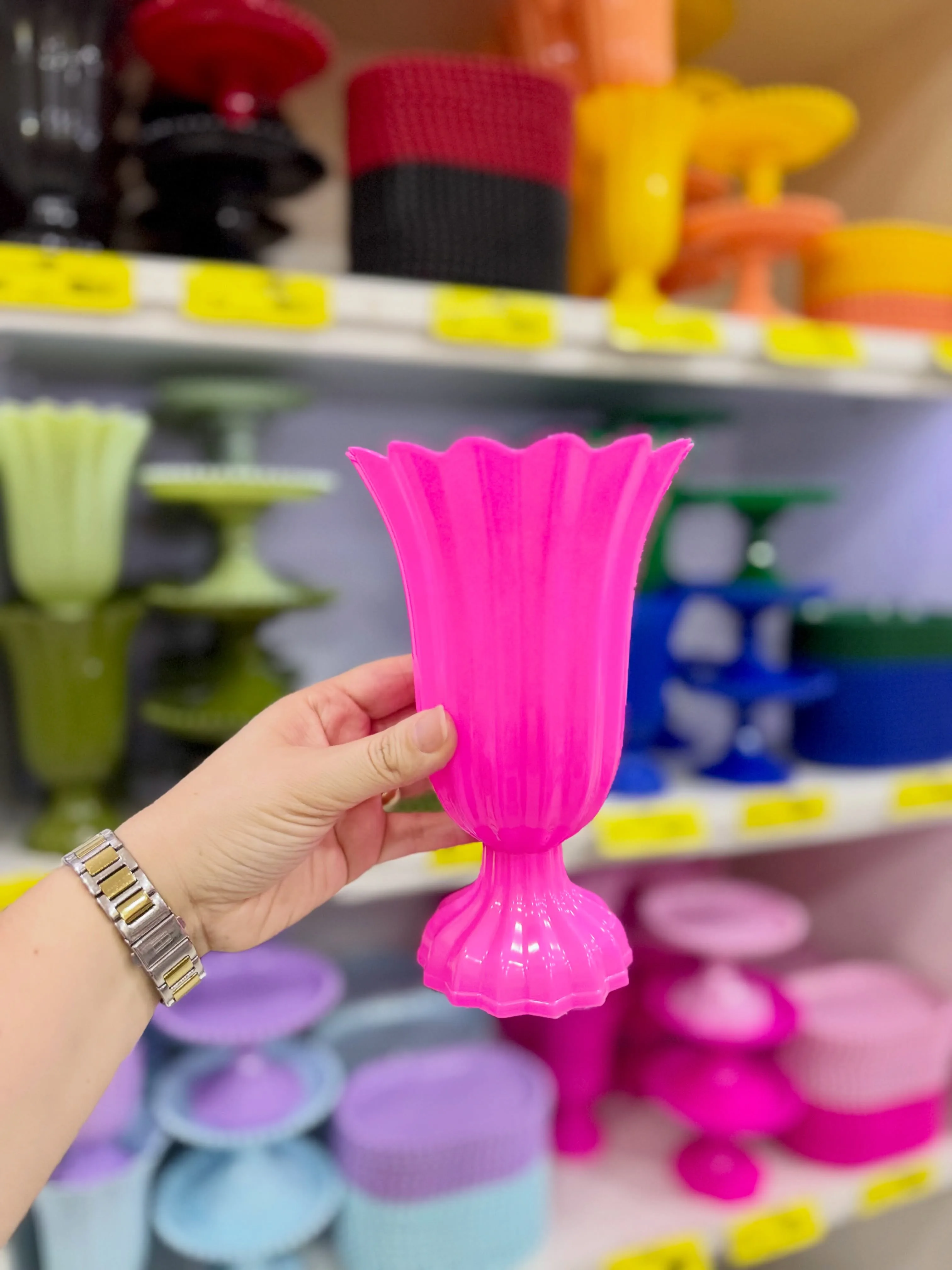 Mão segurando uma peça rosa diante de outras opções coloridas na Karol Festa